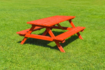 Red picnic table on green lawn in a park