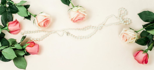 Flowers background. Bouquet of beautiful pink roses and pearl jewelery on  pale pink background.Top view.Copy space