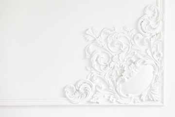 Beautiful ornate white decorative plaster mouldings in studio. The white wall is decorated with exquisite elements of plaster stucco
