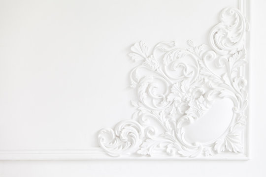Beautiful ornate white decorative plaster mouldings in studio. The white wall is decorated with exquisite elements of plaster stucco