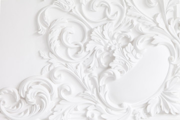 Beautiful ornate white decorative plaster mouldings in studio. The white wall is decorated with exquisite elements of plaster stucco