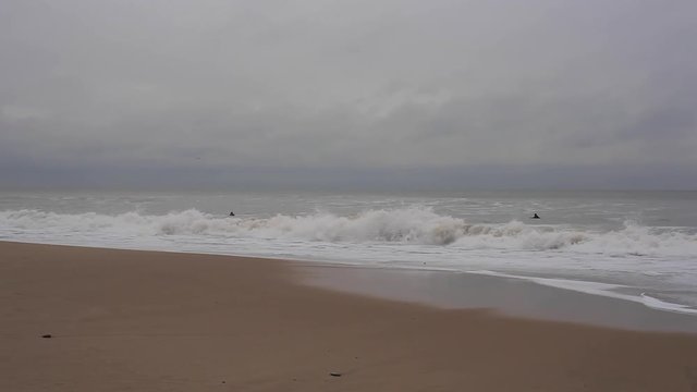 Men are swimming in a sea, wave boarding. Wave covers one. Bright cloudy day. Sunny shore in a foreground. Footage in HD