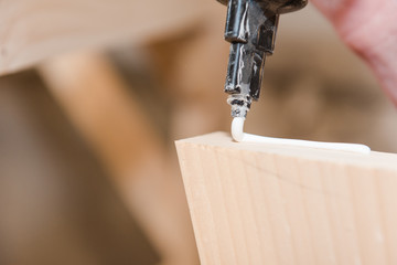 A man squeezes the glue on the wooden part. Carpentry workshop. Professional tool. Strongly glue.