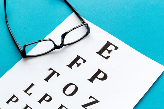 Eye Examination. Eyesight Test Chart And Glasses On Blue Background