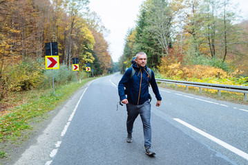 Man walks in the autumn forest along the road. People and lifestyle concept