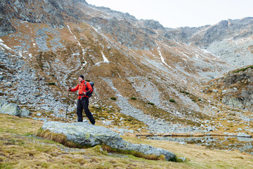 The young man of sporting physique rises to the mountain with sporting equipment