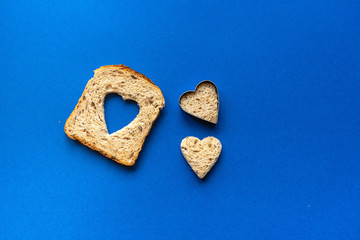 Bread with heart-shaped cut and heart from bread. Wooden Blue Background.