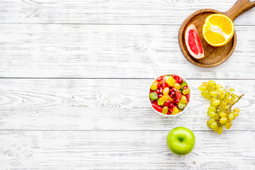 Naklejka na ściany i meble Food rich by vitamins and fiber. Healthy food. Fruit salad near fresh fruits on white wooden background top view copy space