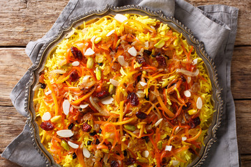 Saffron pilaf with dried fruits, carrots, orange zest, spices and nuts closeup on a plate. Horizontal top view