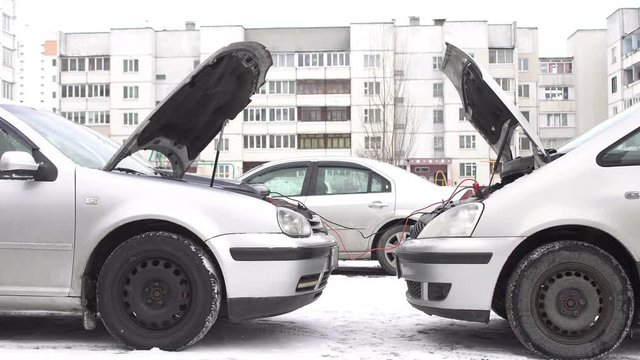 Two cars in the winter using wires to start the engine of the donor, jump start, dead battery
