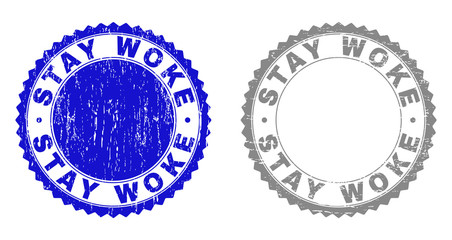 Grunge STAY WOKE watermarks isolated on a white background. Rosette seals with grunge texture in blue and grey colors. Vector rubber stamp imitation of STAY WOKE caption inside round rosette.