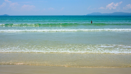 Beautiful sandy beach with a lonely man on a Sunny day. Turquoise clear sea with waves. White sand beach Doc Let, Vietnam