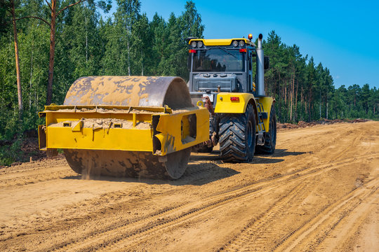 Pneumatic-tired roller compacts the soil in the embankment on the road's construction. sand consolidation on road-building. Yellow compactor driving on the sandy roadbase. soil compacting machine