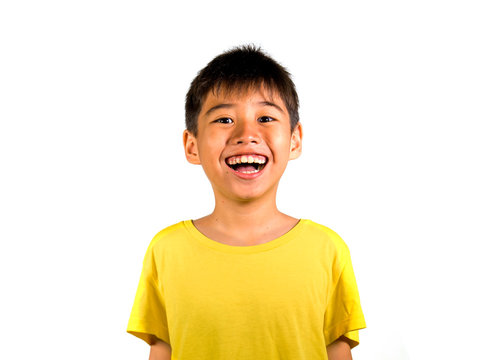 young happy and excited child smiling and laughing cheerful wearing yellow t-shirt isolated on white background in kid happiness and joyful face expression concept
