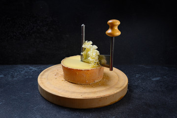 girolle, a special knife for tête de Moine or monk's head cheese to cut thin shavings in form of rosettes, dark slate background with copy space