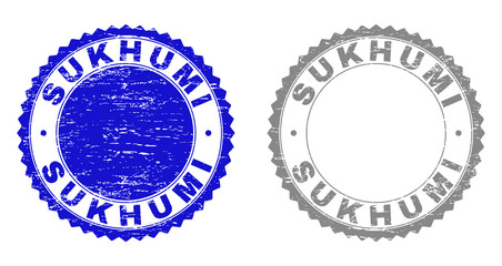 Grunge SUKHUMI watermarks isolated on a white background. Rosette seals with grunge texture in blue and grey colors. Vector rubber stamp imprint of SUKHUMI label inside round rosette.
