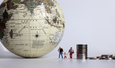 Miniature people and coins. A family of four miniatures walking next to a globe.