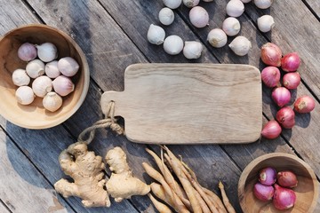 Top view of wooden table full of herbal vegetable ingredients, garlic, red onion, finger root, ginger, copy space