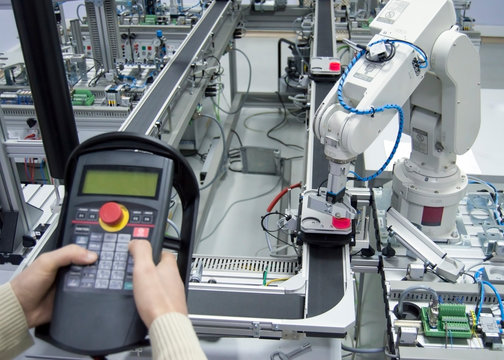 Industry 4.0 concept. Man is holding tablet to control smart factory manufacturing line which is equipped with sensors and robotic arm. industrial automation line. Selective focus.