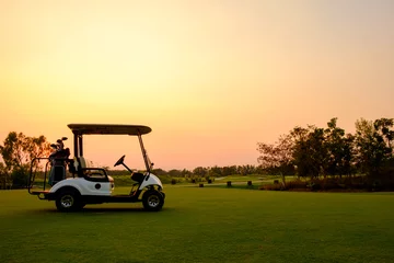 Poster Golf cart car in fairway of golf course with fresh green grass field and cloud sky and tree  on sunset time © ahorizon