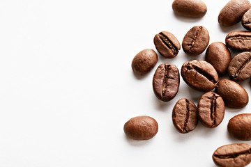 Roasted brown coffee beans scattered on white table with a lot copy space for text. Flat lay composition. Close up, top view, background.
