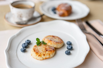 Cottage cheese pancakes or syrniki with blueberry on white plate, closeup view. Russian, Ukrainian cuisine. Healthy tasty breakfast