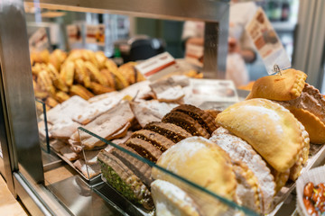 Buns, pies, biscuits and other pastries. Showcase desserts in an Italian cafe or trattoria. Variety of cakes on display.