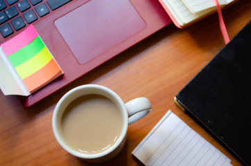 home office desk, red laptop, coffee, notebooks, diary, pen