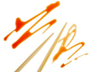 Splashes of soy sauce and chopsticks isolated on white background