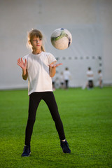 A little girl throwing the ball on the field playing football