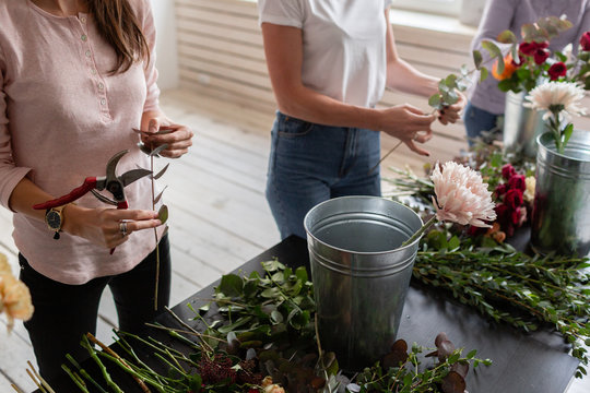Close-up flowers in hand. Florist workplace. Woman arranging a bouquet with roses, chrysanthemum, carnation and other flowers. A teacher of floristry in master classes or courses
