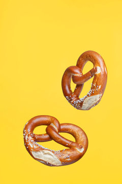 Flying Food Concept German Traditional Salted Pretzel on Yellow Background