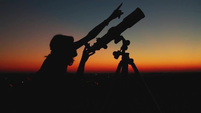 Girl looking through a telescope at the stars.