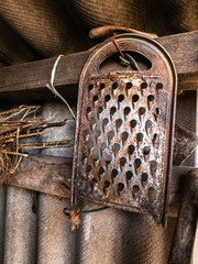 Old rusty grater hanging on a wall, rustic barn, retro background texture
