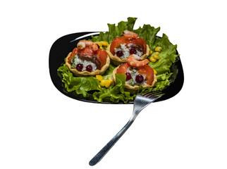 Tartlets with rice and red fish on a leaf of lettuce on a black plate on a white background. Isolate