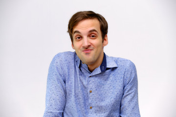 Concept studio portrait of a handsome young man isolated on a white background with different emotions in a blue shirt