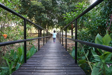Obraz premium Unidentified child is walking through a wooden bridge in the park.