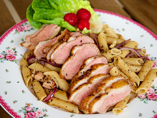 Penne pasta with grilled roast duck breasts slices and olive oil, basils and black peppers. Fusion food.