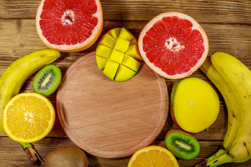 Fototapeta na wymiar Assortment of tropical fruits on wooden table. Still life with bananas, mango, oranges, grapefruit and kiwi fruits
