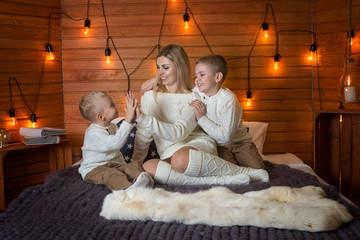 Mom with children in the winter frosty evening lying on the bed together.	