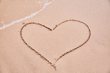 Fototapeta na wymiar Drawing a heart on the sand. Sign of love