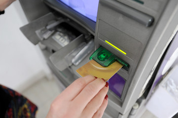 A woman withdraws money from the ATM with credit card and pin code