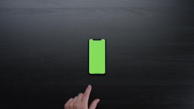 Male hands using smart device with green screen chroma on black clean minimalistic table with top view 4K