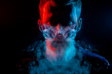 Portrait of a man who is angry and has bad emotions with mask from a smoke around on a black...