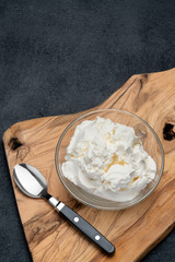Traditional Mascarpone cheese in glass bowl on concrete background
