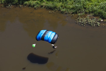 BASE jumper before landing on the water near the river bank. View from above.
