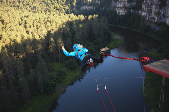 Woman-ropejumper  jumps from a great height against the background of a rocky canyon and a river. Jump with a rope.