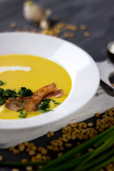 Pea soup with pieces of bacon, parsley and onion in a bowl on a dark background. Pea cream soup.