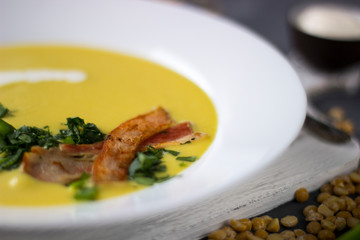 Macro pea soup with pieces of bacon, parsley and onion in a bowl on a dark background. Pea cream soup.