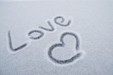 Writing text LOVE on the snow, painted heart on snow